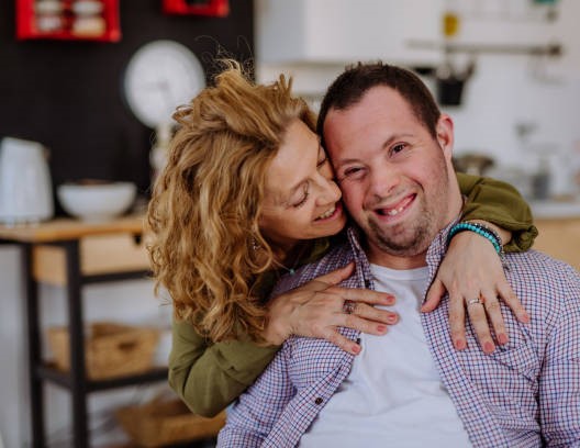 A portrait of mother hugging her grown up son with Down syndrome, motherhood concept.