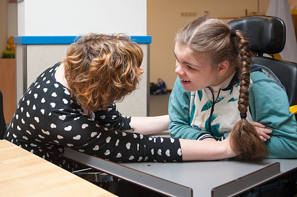 A disabled child in a wheelchair making eye contact with a special needs carer