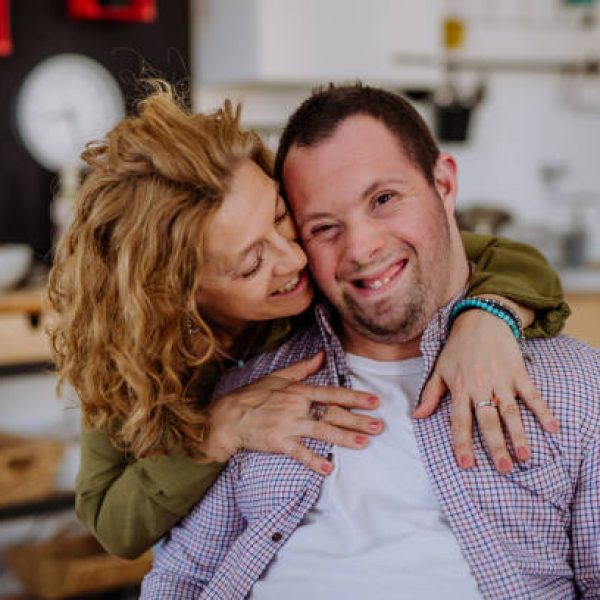 A portrait of mother hugging her grown up son with Down syndrome, motherhood concept.