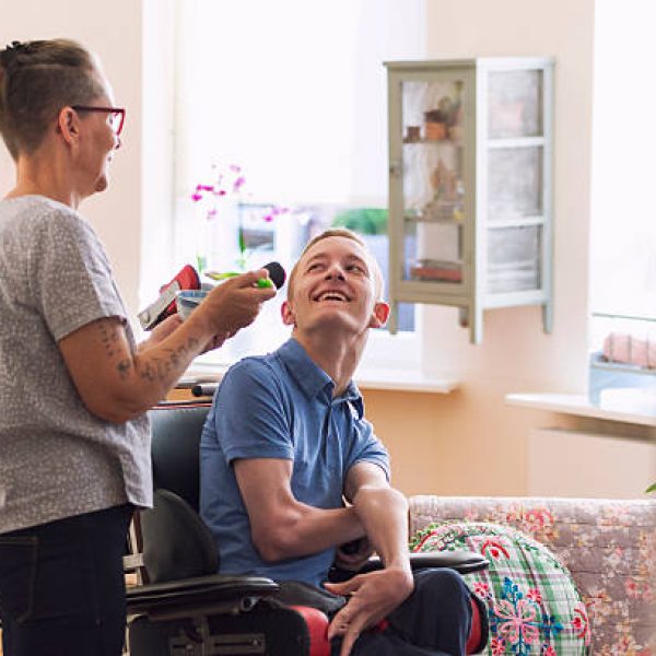 Color image of a real life young physically impaired Cerebral Palsy patient being fed by his mother.